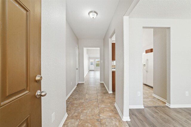 corridor featuring light wood-type flooring and baseboards