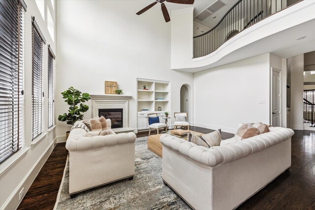 living area featuring baseboards, dark wood finished floors, and a glass covered fireplace