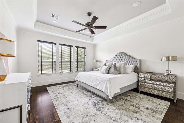 bedroom with dark wood finished floors, a raised ceiling, visible vents, and baseboards