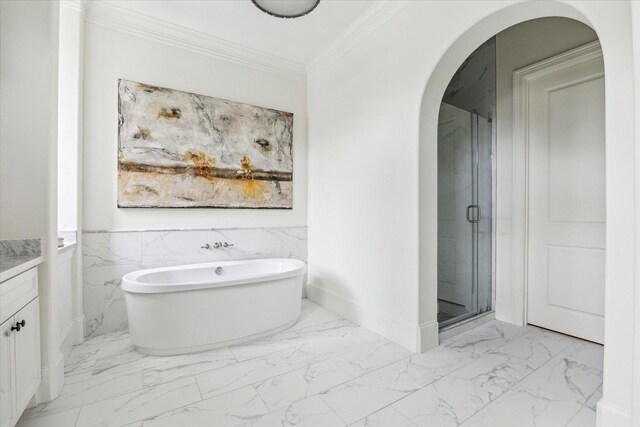 bathroom featuring marble finish floor, crown molding, a soaking tub, vanity, and a shower stall