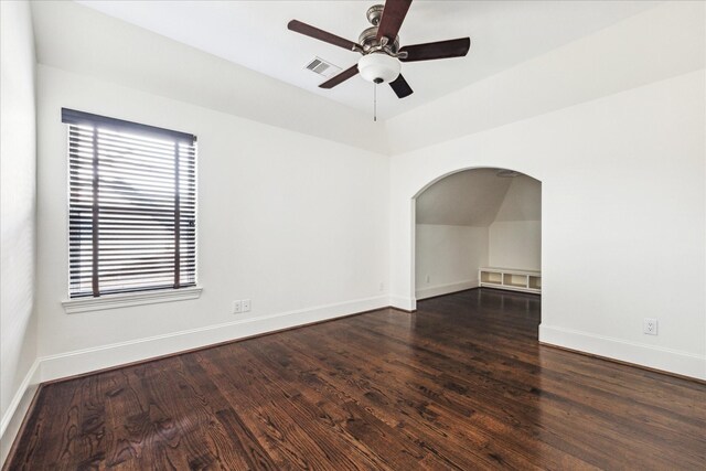 spare room with baseboards, visible vents, dark wood finished floors, and arched walkways