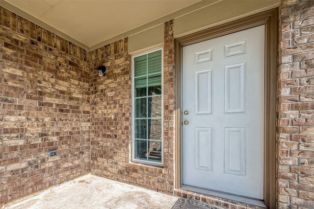 view of exterior entry featuring brick siding and a porch