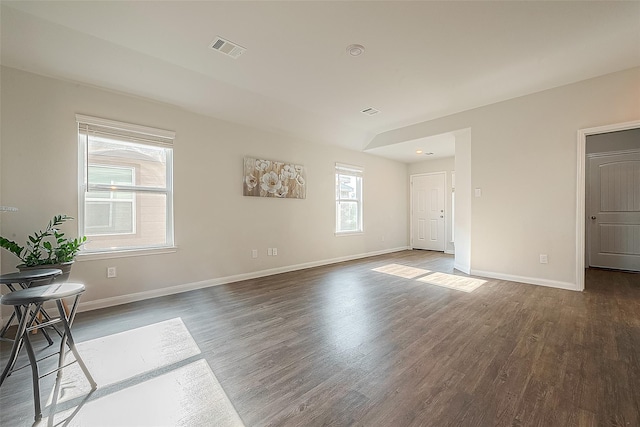 empty room with wood finished floors, visible vents, and baseboards