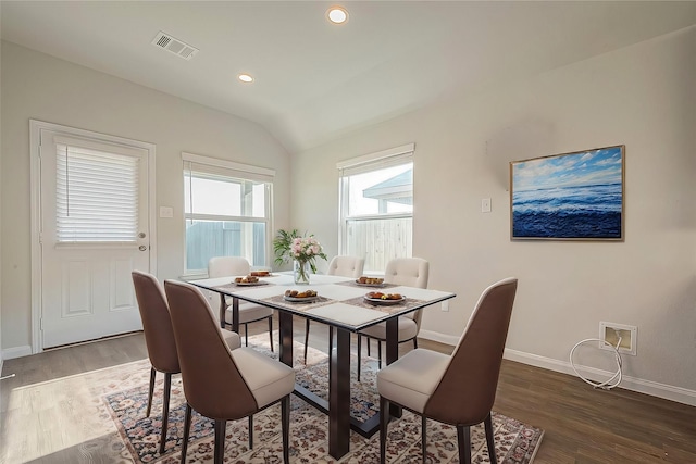 dining space with visible vents, lofted ceiling, baseboards, and wood finished floors