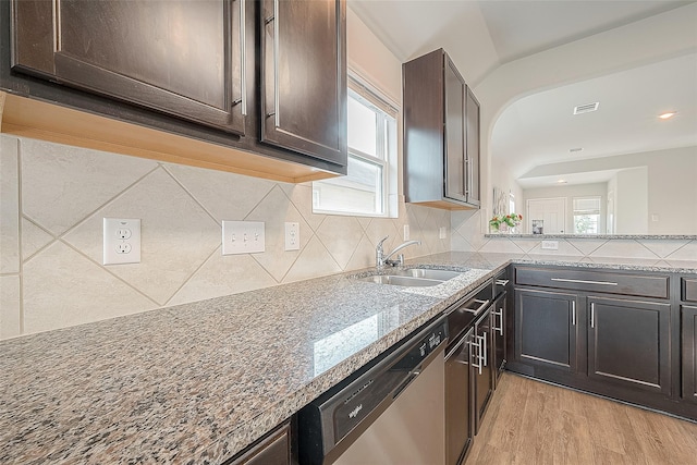 kitchen featuring a sink, tasteful backsplash, stainless steel dishwasher, light wood finished floors, and dark brown cabinets