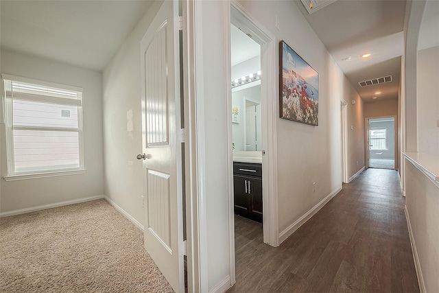 corridor with dark wood finished floors, visible vents, and baseboards