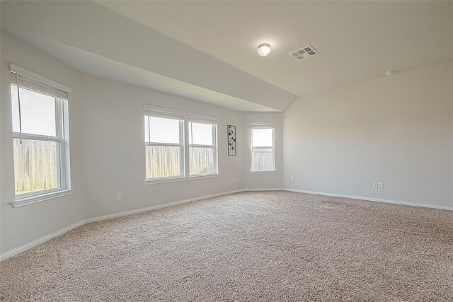 carpeted spare room with lofted ceiling, baseboards, and visible vents