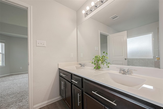 bathroom featuring a sink, visible vents, baseboards, and double vanity