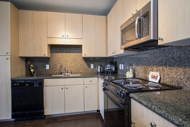 kitchen with dark stone counters, light brown cabinets, a sink, and black appliances