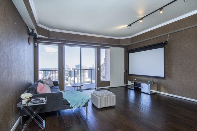 home theater room featuring rail lighting, crown molding, baseboards, and wood finished floors