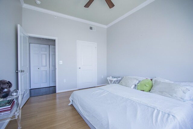 bedroom with baseboards, visible vents, crown molding, and wood finished floors