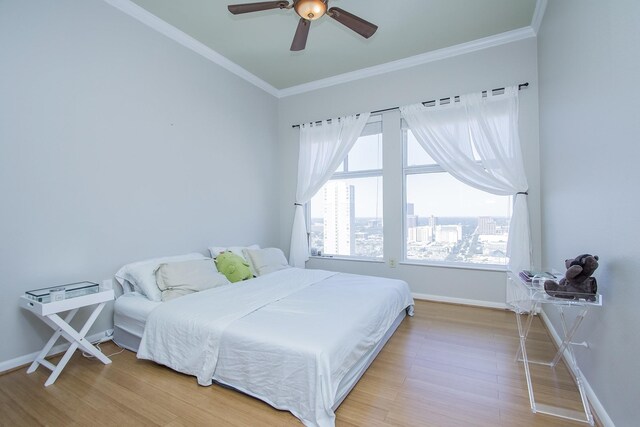 bedroom with baseboards, a ceiling fan, ornamental molding, a city view, and light wood-type flooring