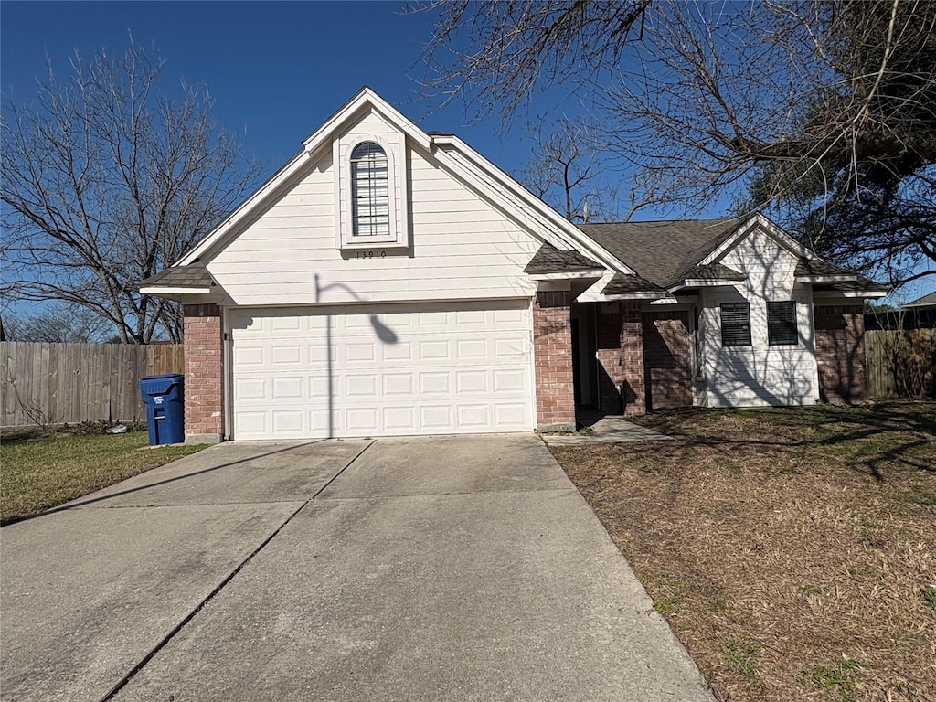 view of front facade with driveway, brick siding, and fence