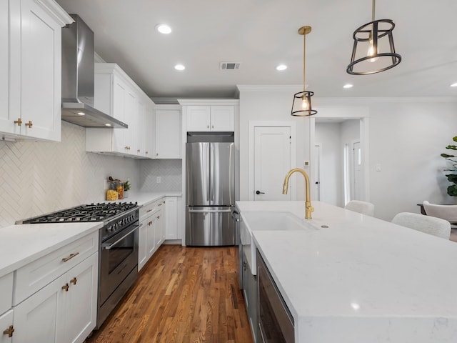 kitchen featuring hanging light fixtures, wall chimney range hood, white cabinetry, and appliances with stainless steel finishes