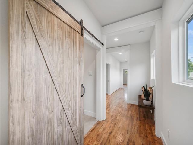 hall featuring recessed lighting, wood finished floors, baseboards, and a barn door