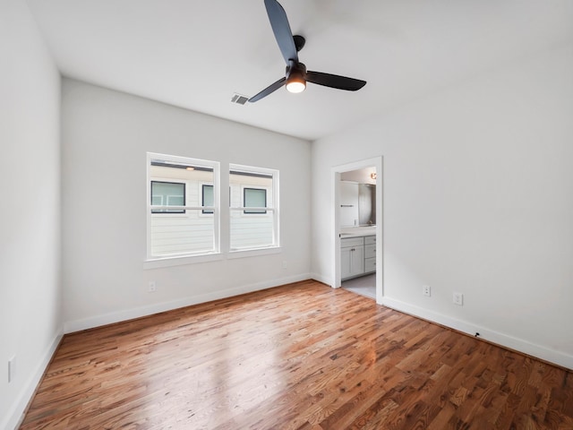 unfurnished bedroom with visible vents, light wood-style flooring, ceiling fan, ensuite bath, and baseboards