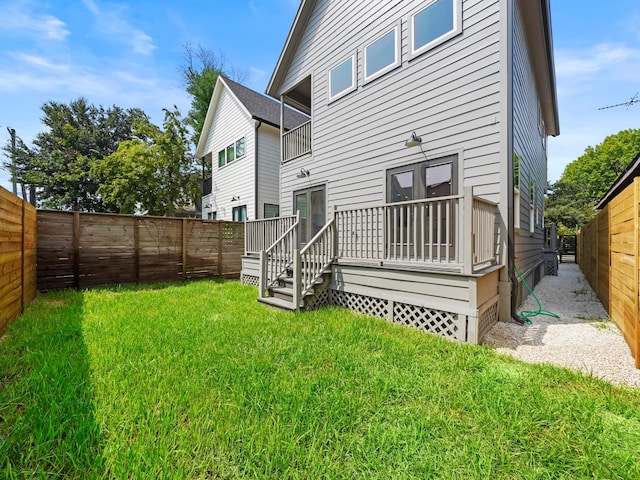 rear view of house with a deck, a yard, and a fenced backyard