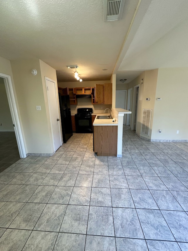 kitchen with a peninsula, light countertops, black appliances, a sink, and light tile patterned flooring