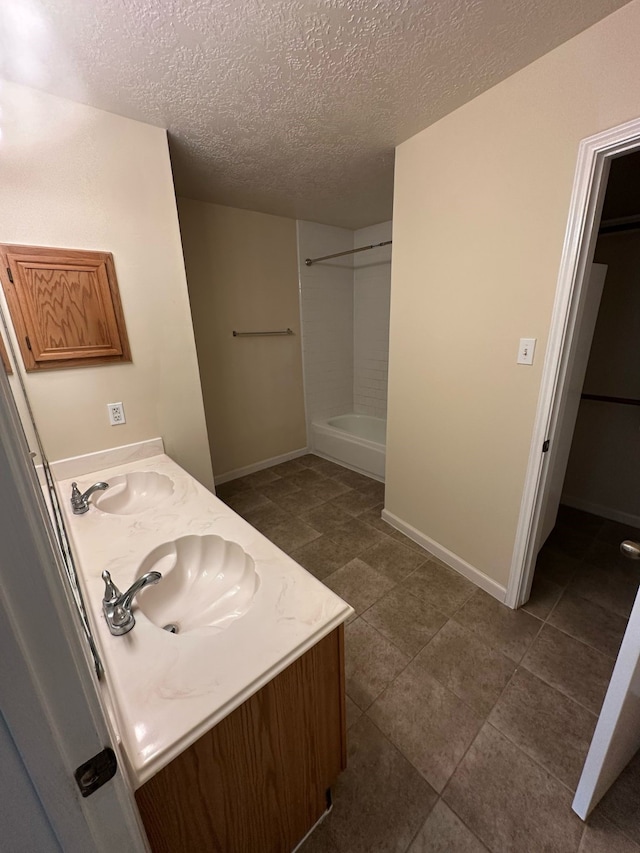 bathroom with a sink, double vanity, and a textured ceiling