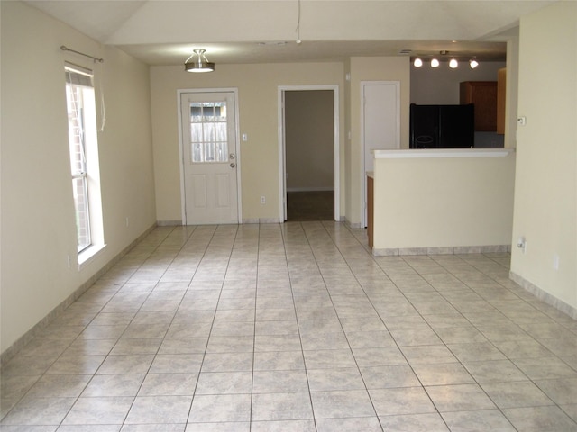 interior space featuring baseboards, lofted ceiling, and light tile patterned flooring