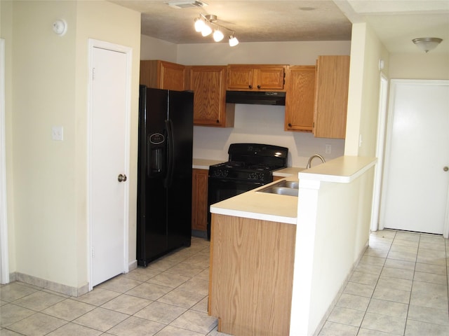 kitchen featuring a sink, light countertops, light tile patterned floors, under cabinet range hood, and black appliances