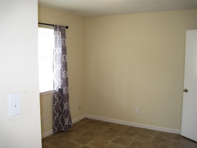 unfurnished room with dark tile patterned flooring, baseboards, and a healthy amount of sunlight