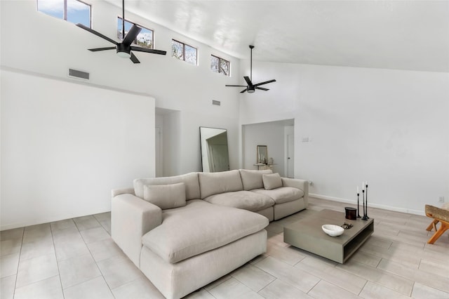 living area with a ceiling fan, visible vents, a towering ceiling, and baseboards