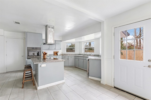 kitchen with visible vents, a center island, oven, island exhaust hood, and gray cabinetry