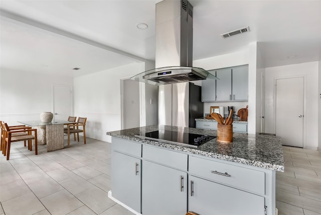 kitchen featuring light tile patterned floors, visible vents, dark stone countertops, island exhaust hood, and black electric stovetop