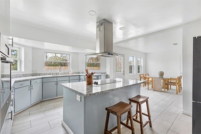 kitchen with island exhaust hood, a wealth of natural light, gray cabinets, a kitchen island, and black electric cooktop