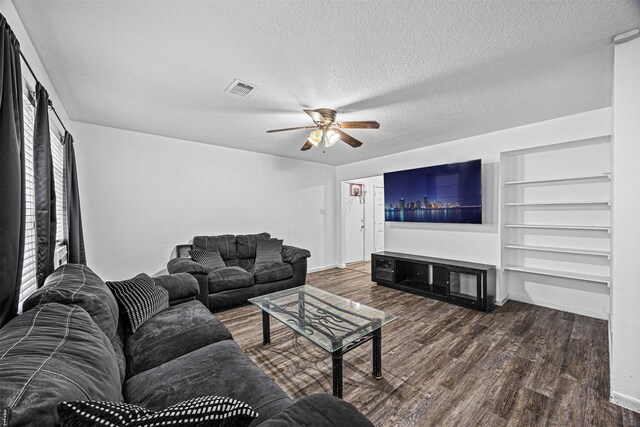 living area with ceiling fan, a textured ceiling, visible vents, and dark wood-style flooring