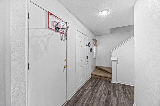 foyer entrance with dark wood-style floors, stairs, baseboards, and a textured ceiling