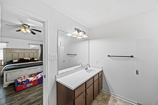 ensuite bathroom with a textured wall, ensuite bathroom, vanity, a textured ceiling, and baseboards