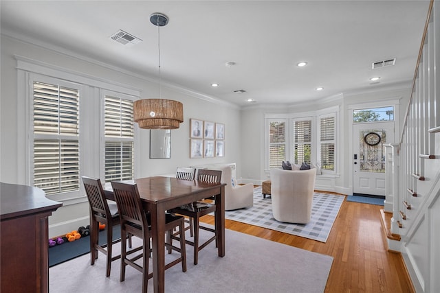 dining area with visible vents, crown molding, light wood finished floors, and stairs