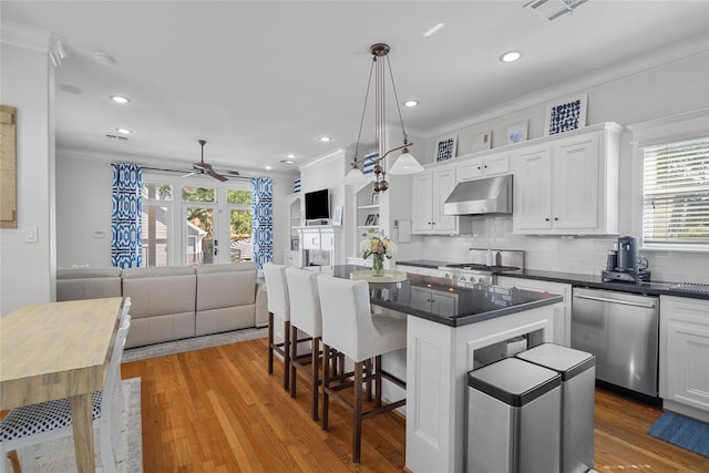 kitchen featuring dark countertops, under cabinet range hood, white cabinetry, and open floor plan