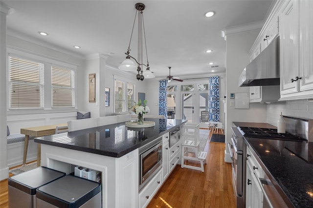 kitchen featuring a center island, decorative light fixtures, appliances with stainless steel finishes, white cabinets, and extractor fan