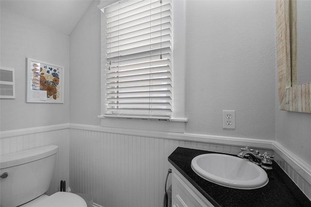 bathroom featuring a wainscoted wall, vanity, and toilet