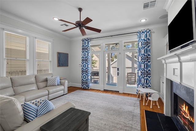 living area featuring visible vents, wood finished floors, a high end fireplace, and crown molding