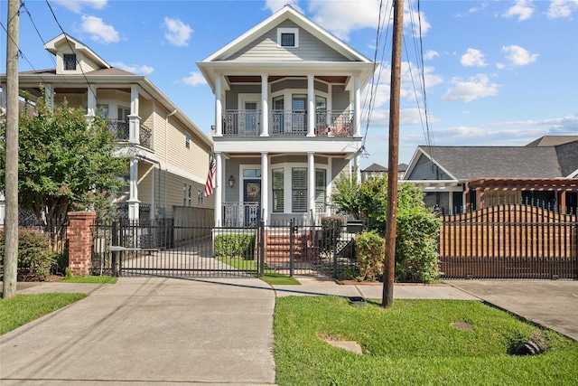 view of front of home featuring a balcony, a fenced front yard, a gate, and a porch