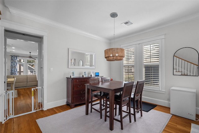 dining space featuring ornamental molding, wood finished floors, visible vents, and baseboards