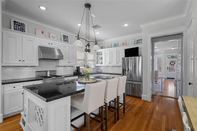 kitchen featuring appliances with stainless steel finishes, a kitchen island, white cabinets, and under cabinet range hood