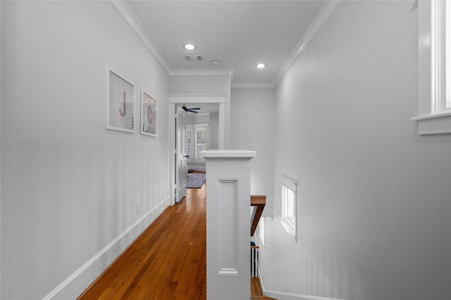 hallway with plenty of natural light, visible vents, crown molding, and wood finished floors