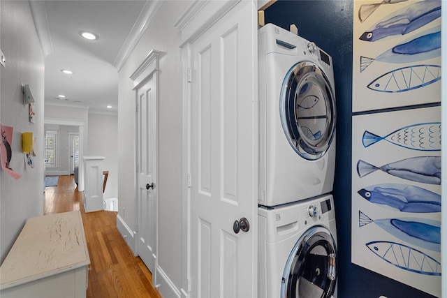 laundry room featuring laundry area, ornamental molding, wood finished floors, stacked washing maching and dryer, and recessed lighting