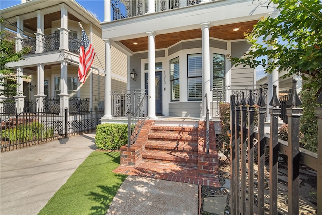 view of exterior entry featuring fence and a porch