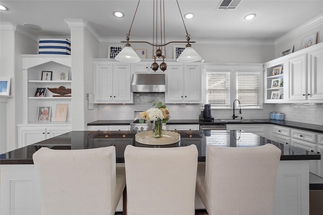 kitchen with under cabinet range hood, a kitchen island, white cabinetry, open shelves, and dark countertops