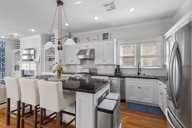 kitchen with stainless steel appliances, dark countertops, white cabinets, and a kitchen island