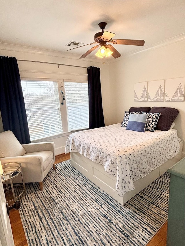 bedroom featuring crown molding, visible vents, ceiling fan, and wood finished floors