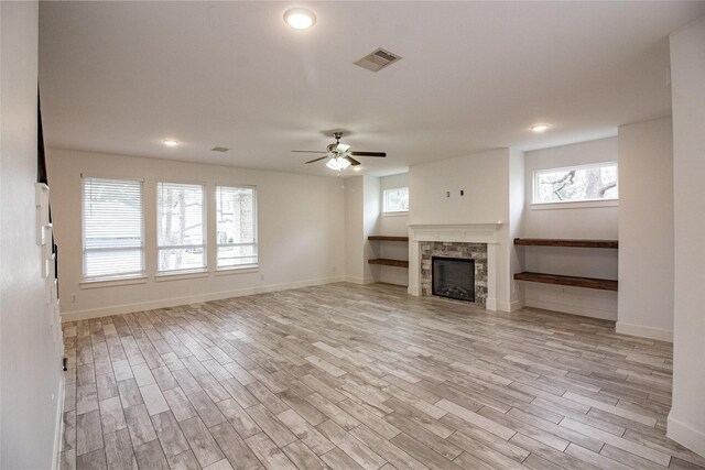 unfurnished living room featuring light wood-style floors, ceiling fan, a fireplace, and visible vents