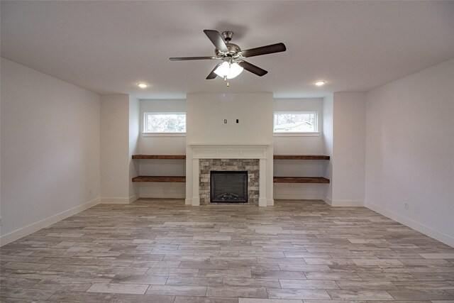 unfurnished living room with baseboards, a fireplace, and light wood-style floors