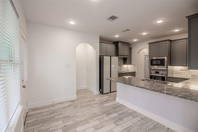 kitchen with arched walkways, oven, visible vents, freestanding refrigerator, and built in microwave